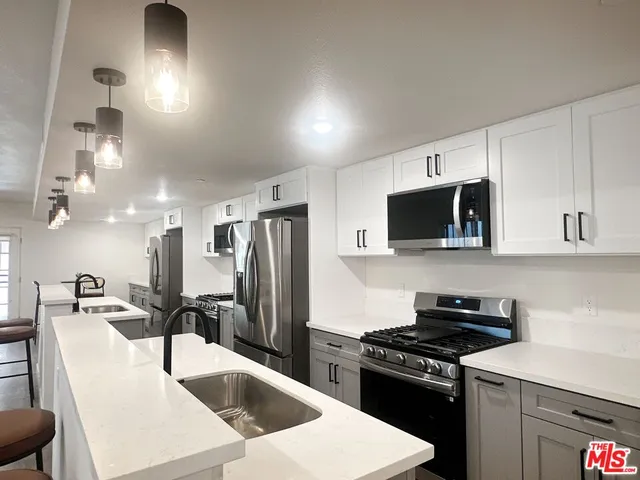 a kitchen with stainless steel appliances a sink a stove a microwave a refrigerator a counter top space and cabinets