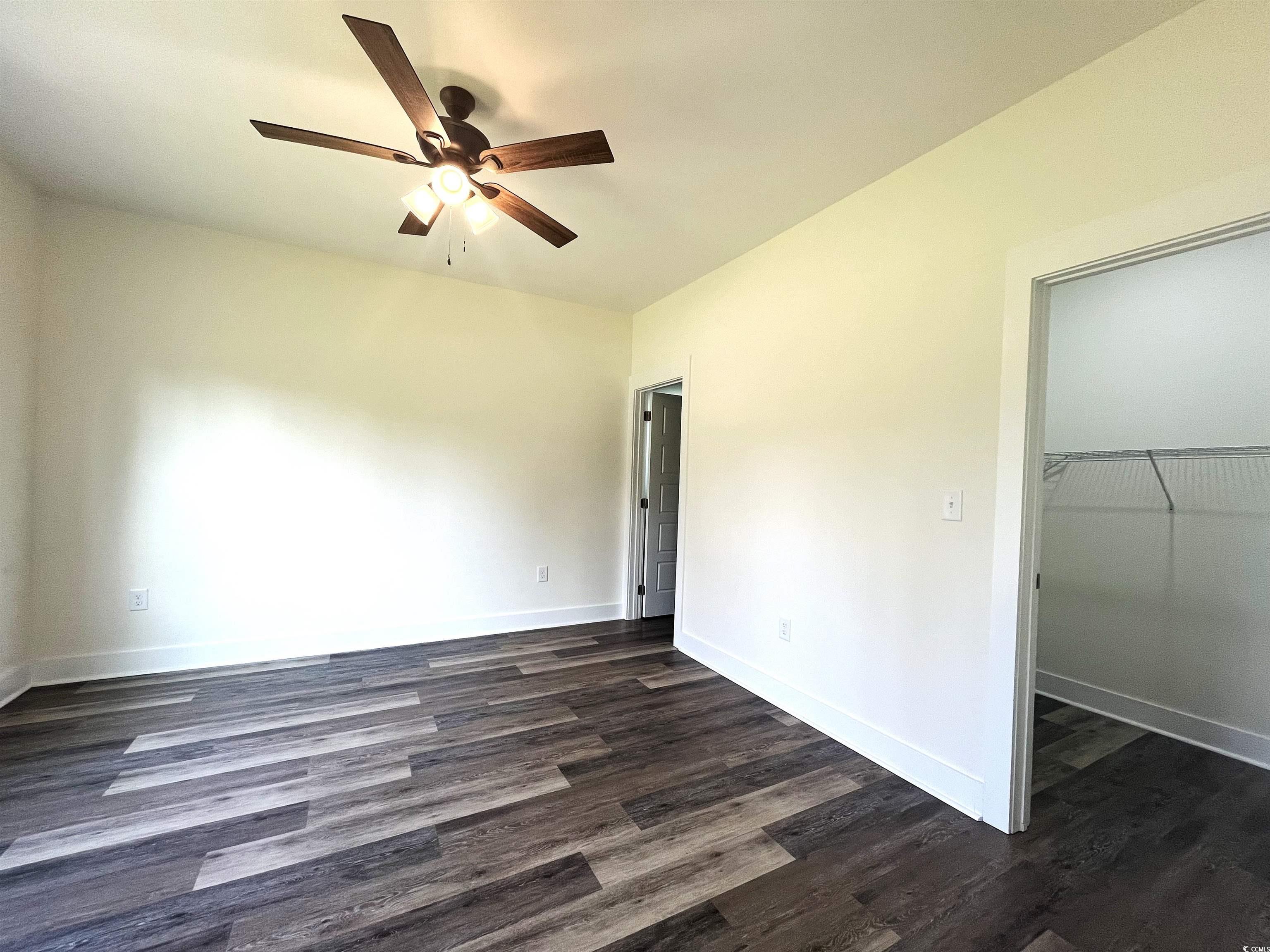 1174 St John Road Galivants Ferry, SC 29544 - Photo 13 of 22 Unfurnished bedroom featuring dark wood-style floors, a closet, a walk in closet, and a ceiling fan