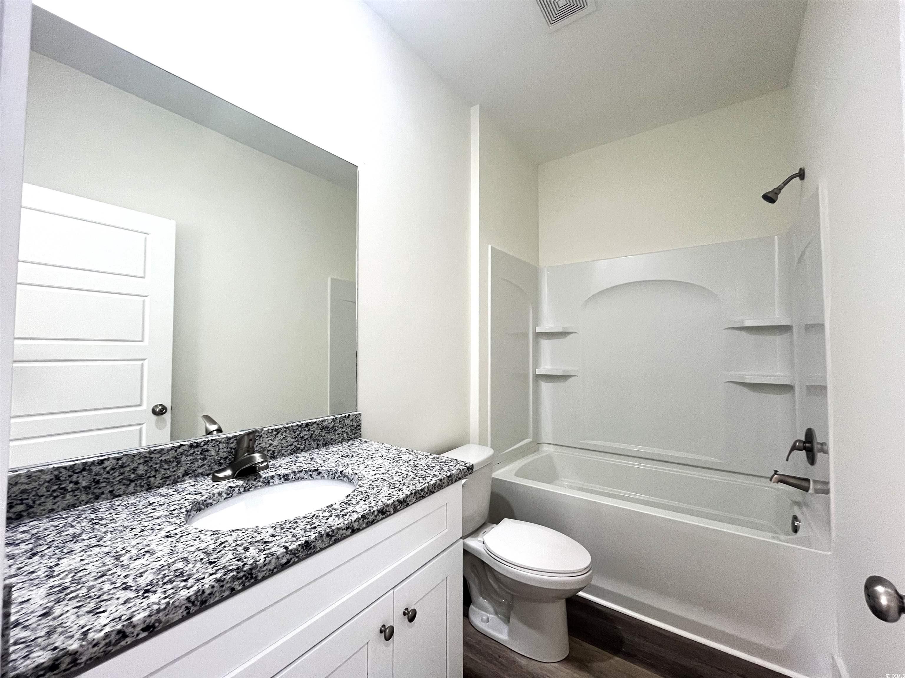 1174 St John Road Galivants Ferry, SC 29544 - Photo 18 of 22 Full bathroom featuring wood finished floors, vanity, and washtub / shower combination