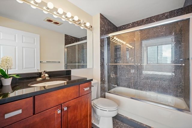 a bathroom with a granite countertop sink mirror toilet and bathtub