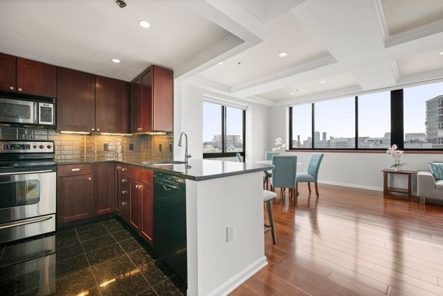 a kitchen with stainless steel appliances granite countertop a stove top oven a sink dishwasher a dining table and chairs with wooden floor