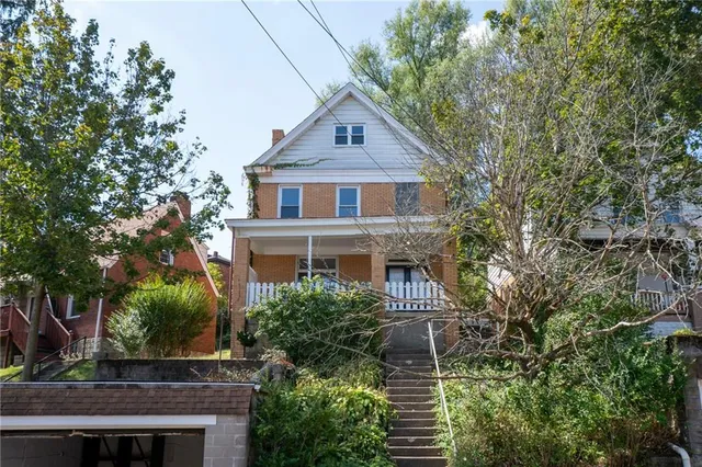 a front view of a house with plants and trees
