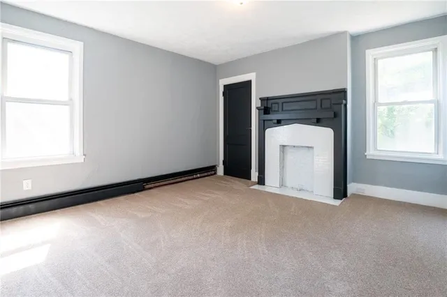 an empty room with a fireplace and windows