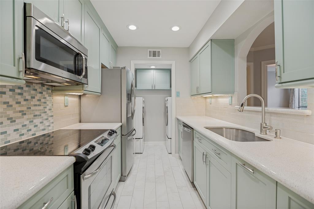 16301 Ledgemont Lane, Unit 263 Addison, TX 75001 - Photo 2 of 25 Galley kitchen featuring light green cabinetry, integrated stainless steel appliances, and solid surface countertops
