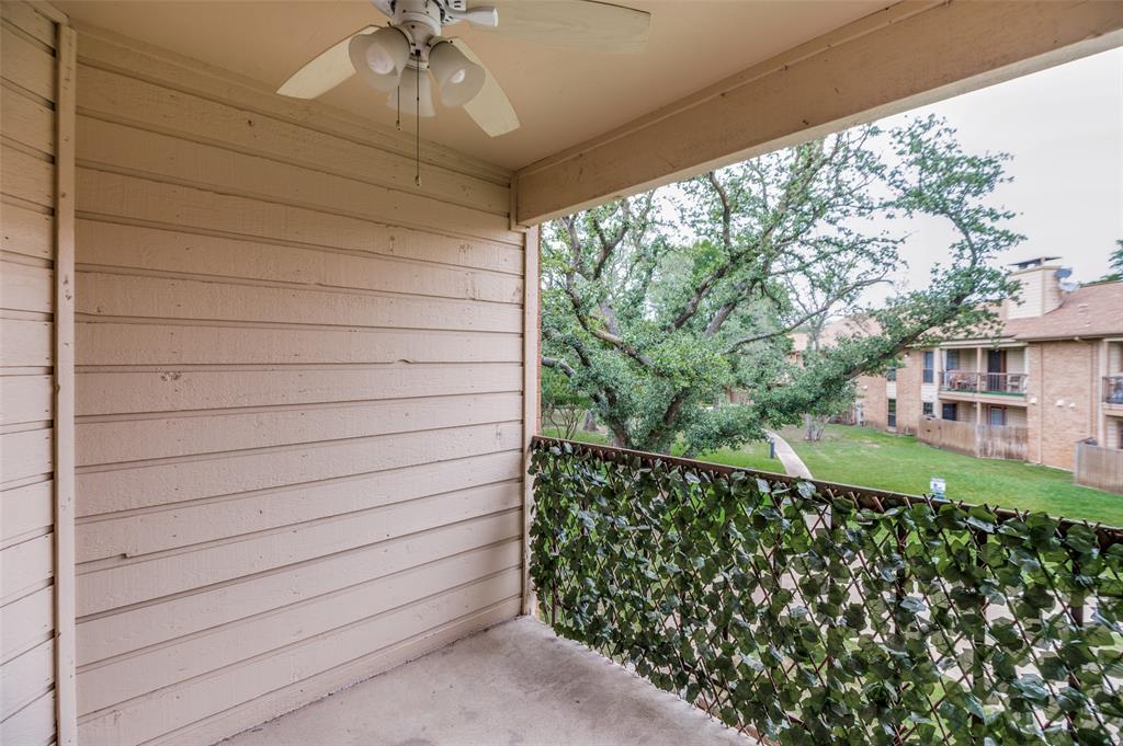 16301 Ledgemont Lane, Unit 263 Addison, TX 75001 - Photo 23 of 25 Spacious living area featuring wood-finish flooring, a white brick fireplace with a mantle, and a ceiling fan with integrated lighting