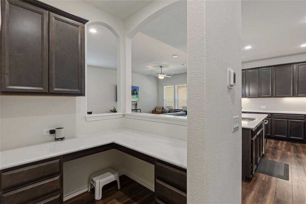 9517 Sunset Lane Oak Point, TX 75068 - Photo 16 of 40 9517 Sunset Lane, Oak Point, TX 75068 - kitchen - Kitchen featuring dark wood finish cabinetry, dark wood-type flooring, built in study area, recessed lighting, and a textured wall