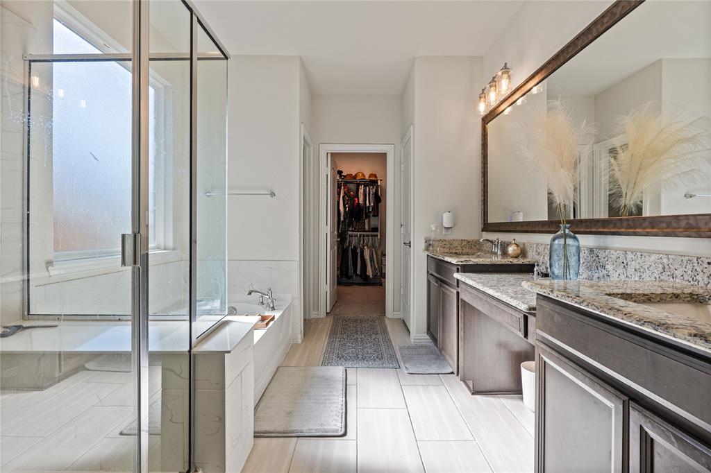 9517 Sunset Lane Oak Point, TX 75068 - Photo 21 of 40 9517 Sunset Lane, Oak Point, TX 75068 - primary bathroom - Primary bathroom featuring double vanity, a spacious closet, a stall shower, and healthy amount of natural light