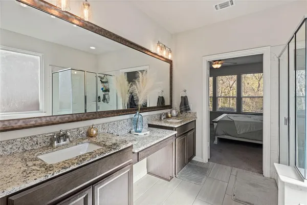 a en suite bathroom with a granite countertop double vanity and a large mirror