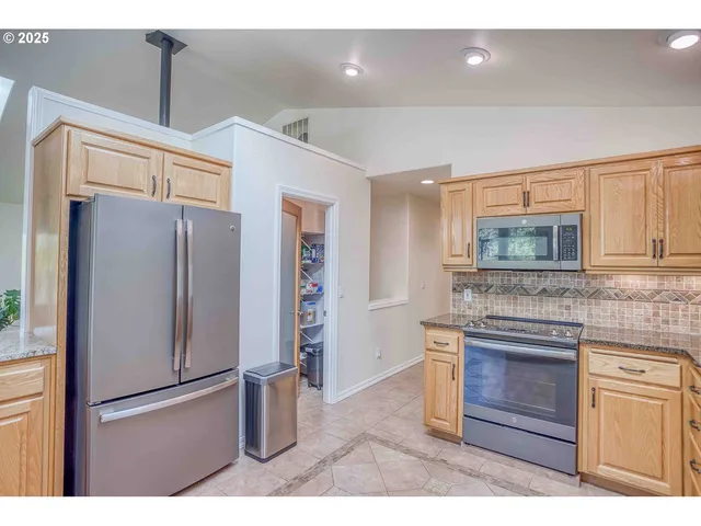 a kitchen with stainless steel appliances granite countertop a refrigerator and a stove top oven