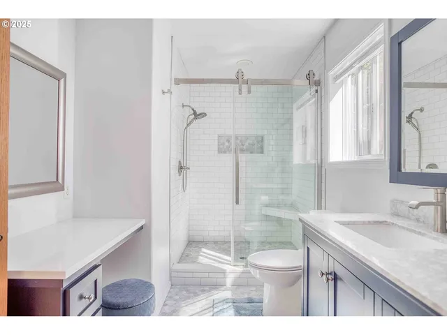 a bathroom with a granite countertop sink a toilet a mirror and shower