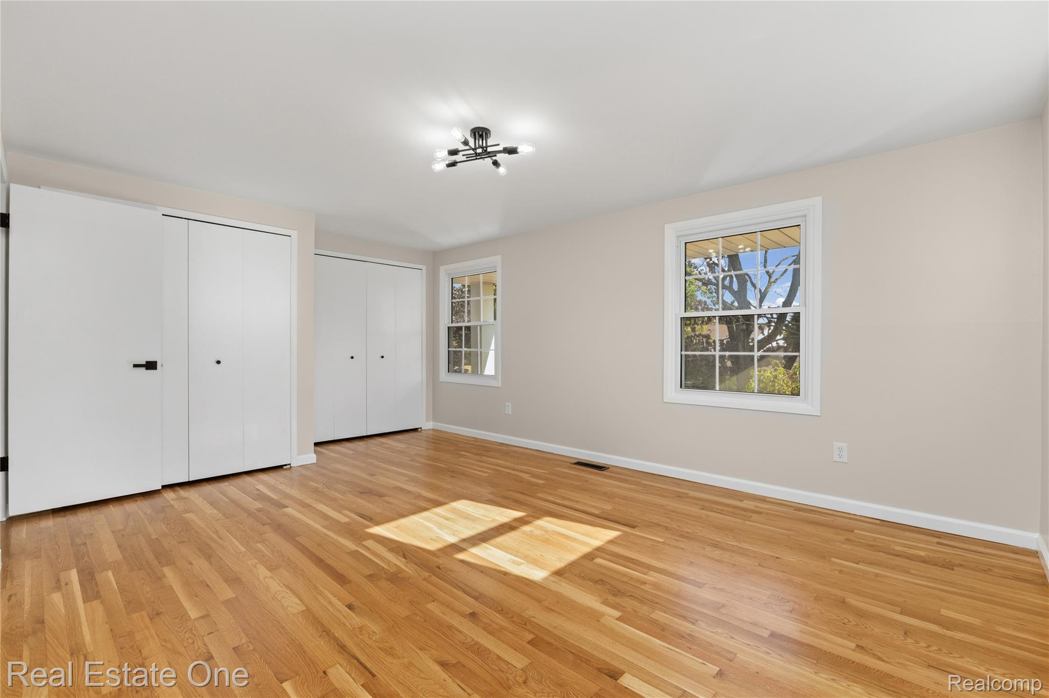25695 Branchaster Road Farmington, MI 48336 - Photo 31 of 58 Hardwood flooring, multiple windows, flush-mount lighting, and white closet doors with dark hardware