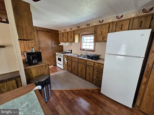 a kitchen with a refrigerator a stove a sink dishwasher a dining table and chairs with wooden floor