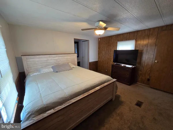 a bedroom with a bed and a flat tv screen on dresser