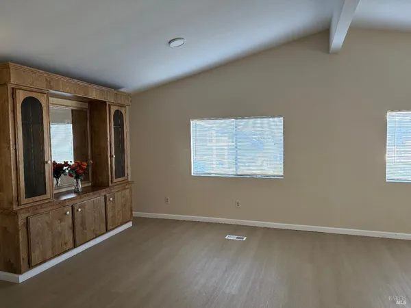 an empty room with wooden floor and cabinet
