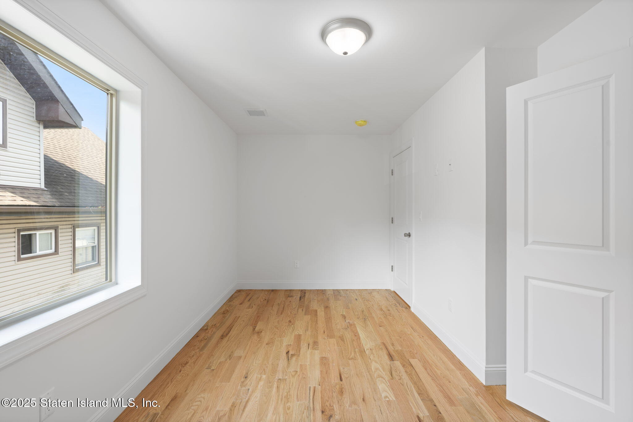 1372 Forest Hill Road, Unit 1A Staten Island, NY 10314 - Photo 16 of 25 a view of a room with wooden floor and white walls
