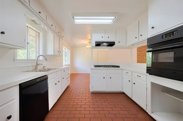 a kitchen with granite countertop white cabinets stainless steel appliances a sink and a window