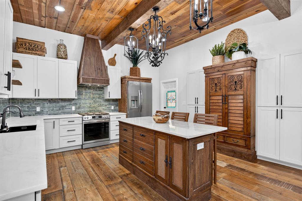 702 West Spring Street Weatherford, TX 76086 - Photo 21 of 39 Kitchen featuring a wood-finish plank ceiling with exposed beams, white cabinetry, a wood-finish island with a light-toned countertop, stainless steel appliances, and a tiled backsplash