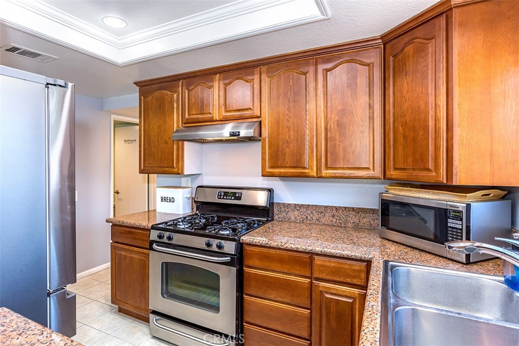 7065 9th Street, Unit 1 Buena Park, CA 90621 - Photo 9 of 36 a kitchen with stainless steel appliances granite countertop a stove a refrigerator and a microwave