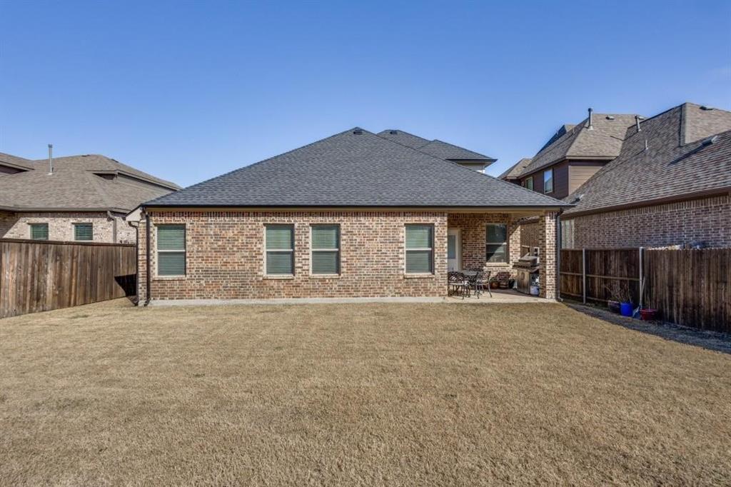 2821 Inn Kitchen Way McKinney, TX 75071 - Photo 21 of 24 Brick exterior with multiple windows, covered patio, and fenced yard
