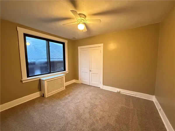 an empty room with a chandelier fan and windows