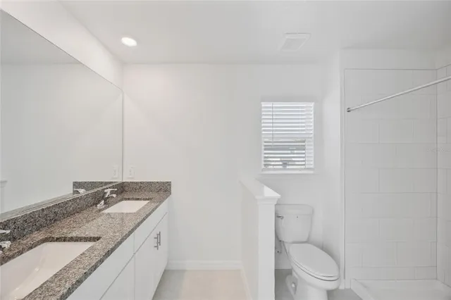 a bathroom with a granite countertop sink toilet and mirror
