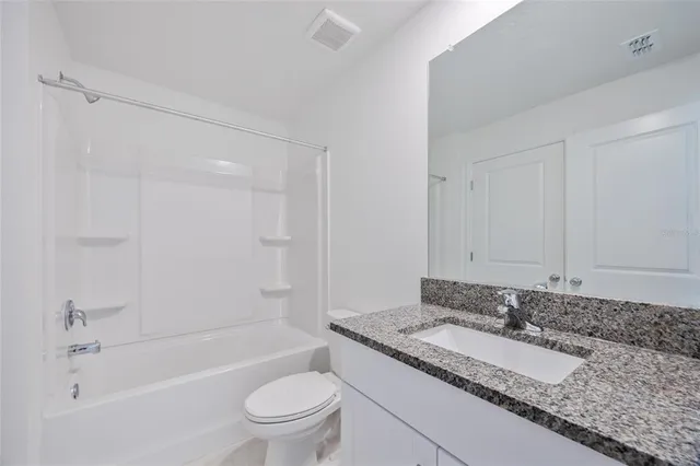 a bathroom with a granite countertop tub sink and mirror