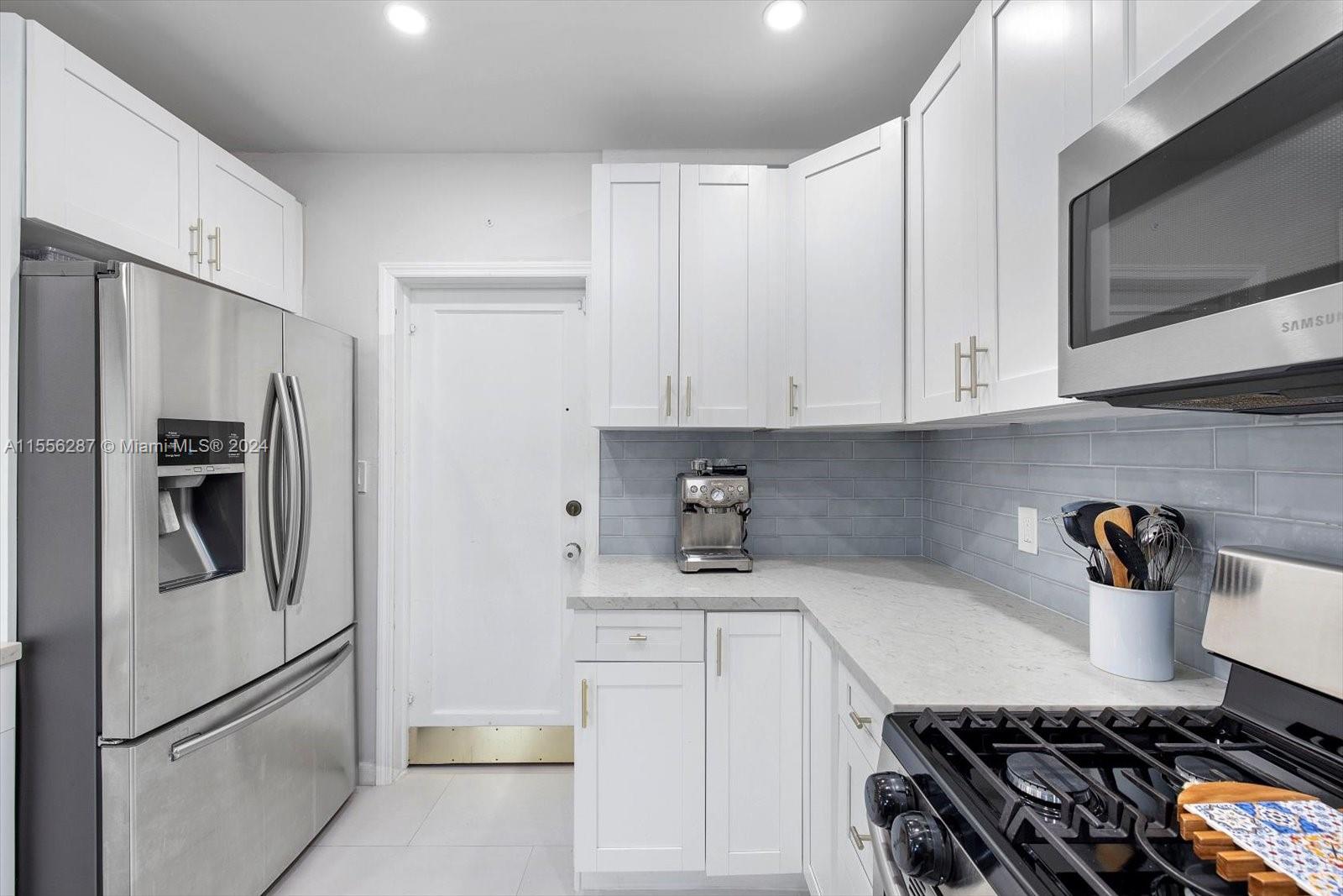 4631 Southwest 12th Street Miami, FL 33134 - Photo 12 of 28 a kitchen with refrigerator a stove and white cabinets
