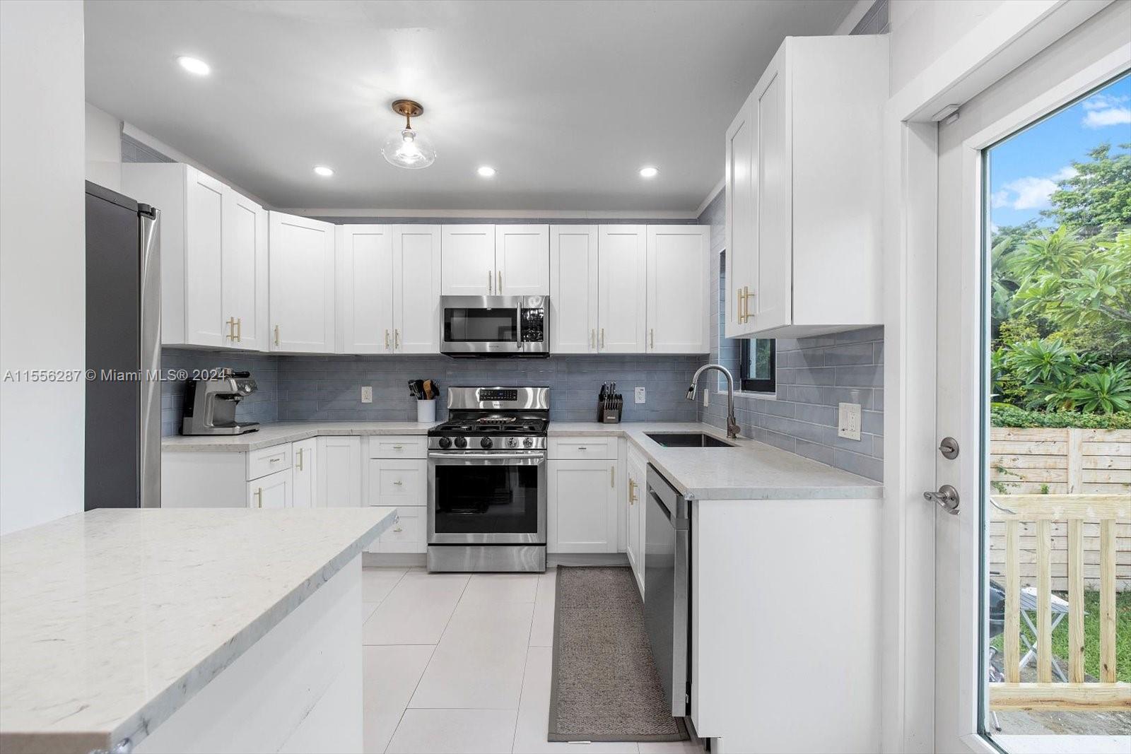 4631 Southwest 12th Street Miami, FL 33134 - Photo 13 of 28 a kitchen with stainless steel appliances granite countertop a stove a sink a refrigerator and white cabinets with wooden floor