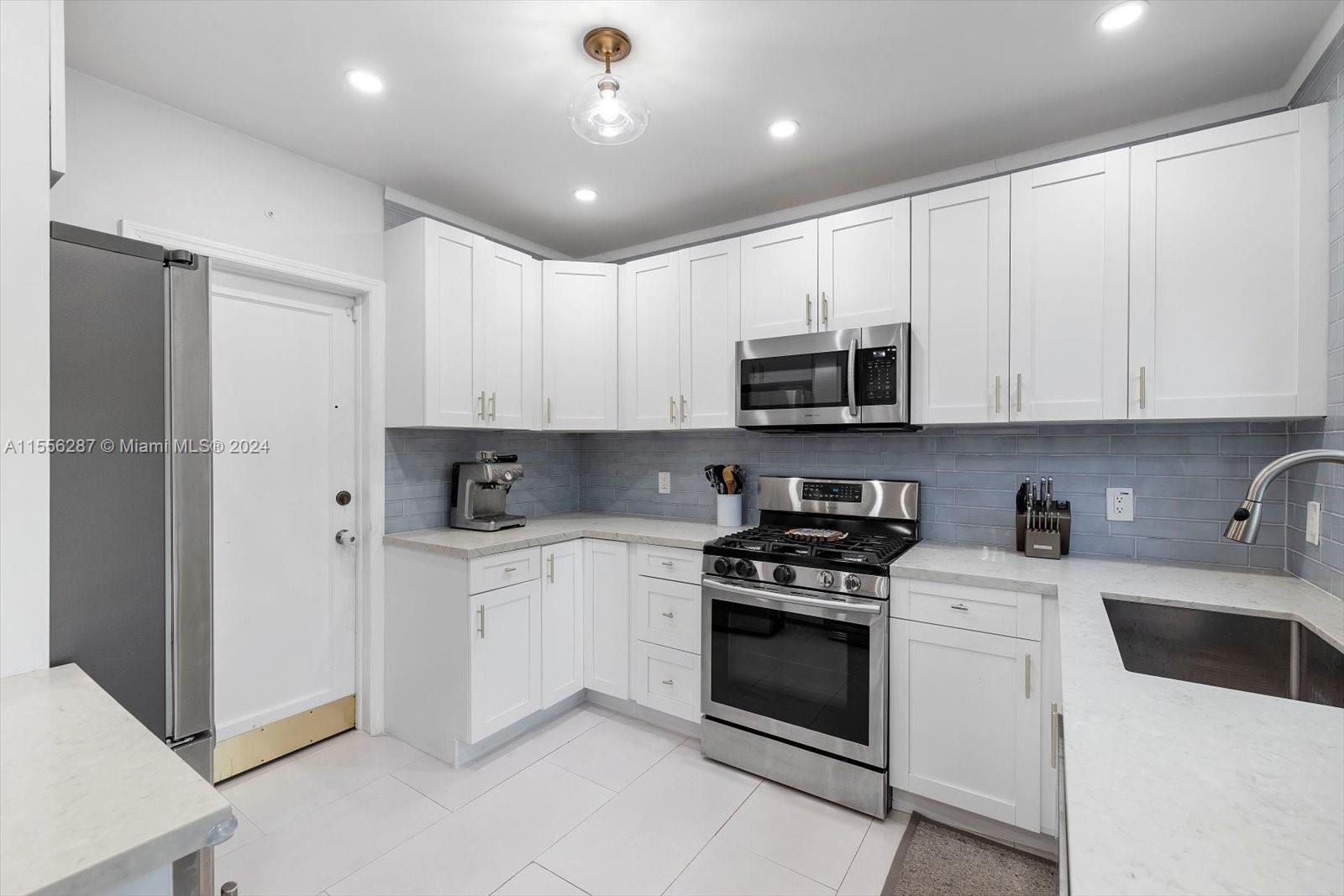 4631 Southwest 12th Street Miami, FL 33134 - Photo 15 of 28 a kitchen with granite countertop white cabinets and stainless steel appliances
