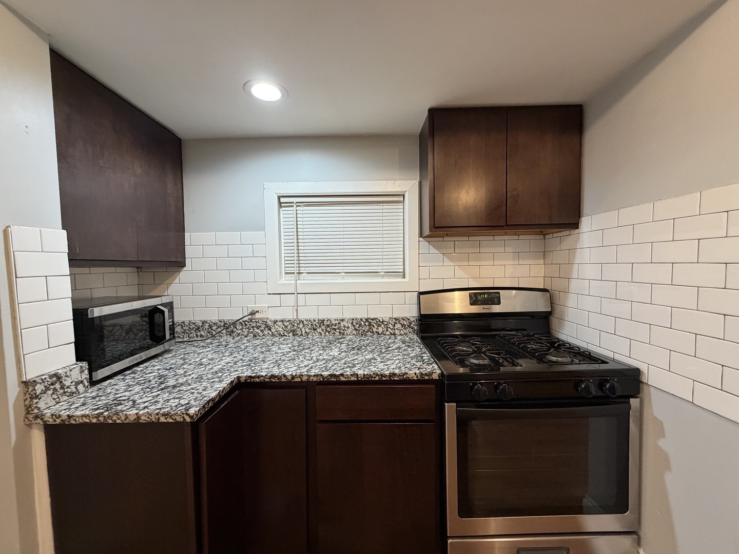 3614 West George Street, Unit 2R Chicago, IL 60618 - Photo 3 of 12 a kitchen with granite countertop stainless steel appliances and wooden cabinets