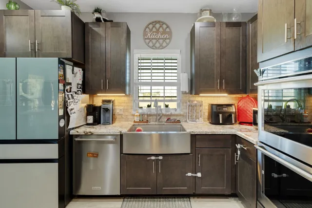 a kitchen with stainless steel appliances a sink a stove a refrigerator and cabinets