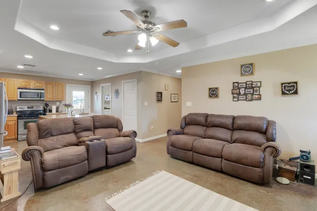 a living room with furniture kitchen view and a chandelier