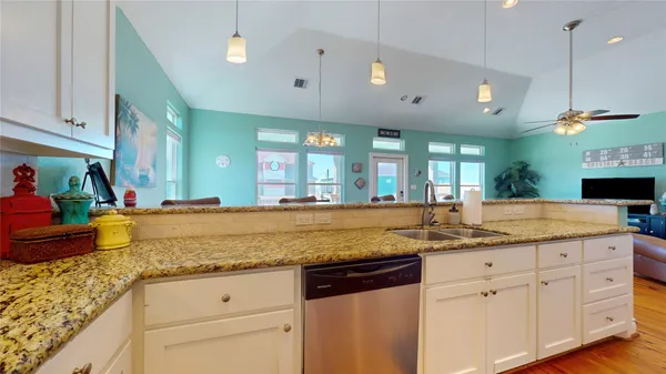 a kitchen with granite countertop a sink cabinets and wooden floor