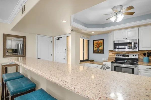 a large kitchen with stainless steel appliances granite countertop a stove oven and a refrigerator with white cabinets