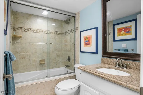 a bathroom with a granite countertop sink a mirror a bathtub and shower