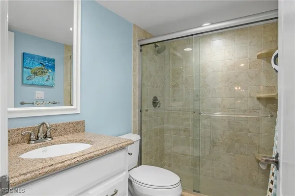 a bathroom with a granite countertop sink toilet a mirror a vanity and shower