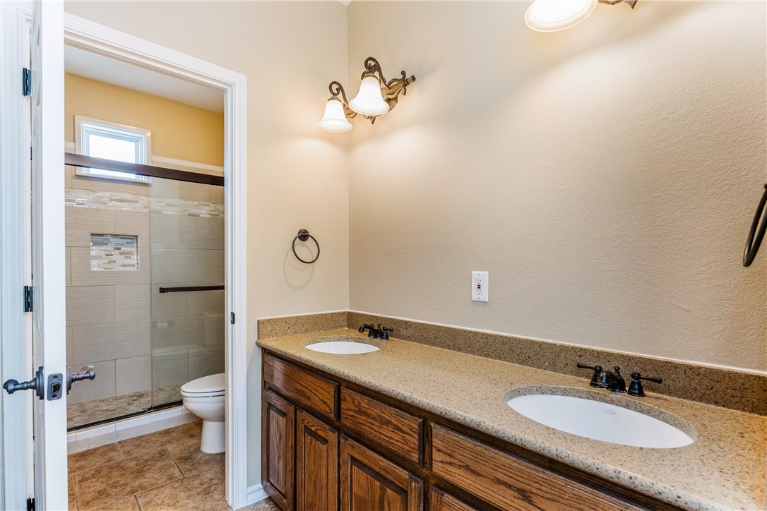 307 Heathercrest Portland, TX 78374 - Photo 32 of 40 a bathroom with a granite countertop sink a toilet and a shower