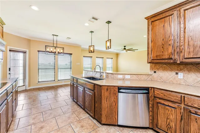 a kitchen with stainless steel appliances granite countertop a sink a stove and a wooden cabinets
