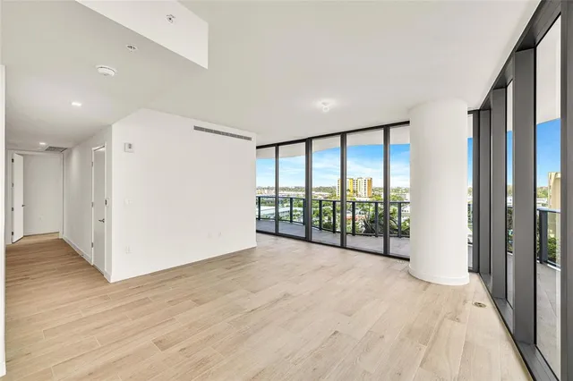 an empty room with wooden floor and windows with view