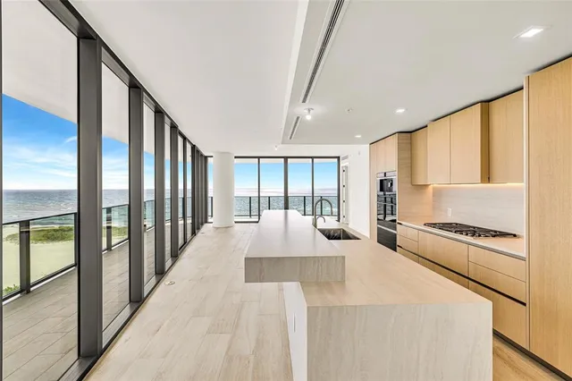 a large white kitchen with kitchen island a large window cabinets and stainless steel appliances
