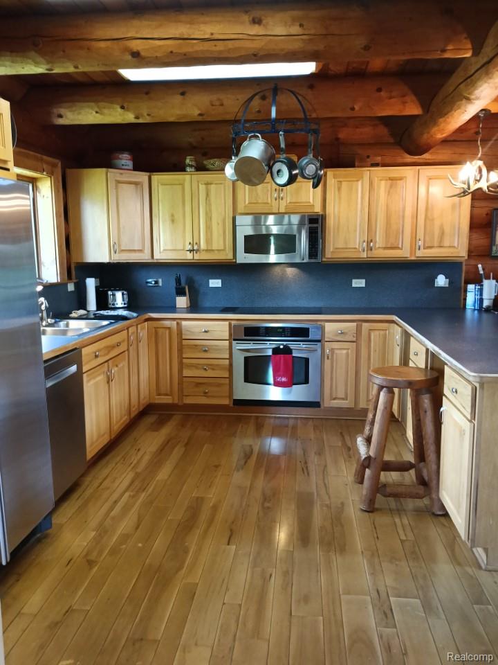 10374 Wilson Road Otisville, MI 48463 - Photo 45 of 99 Kitchen featuring a chandelier, appliances with stainless steel finishes, dark countertops, light wood finished floors, and decorative backsplash