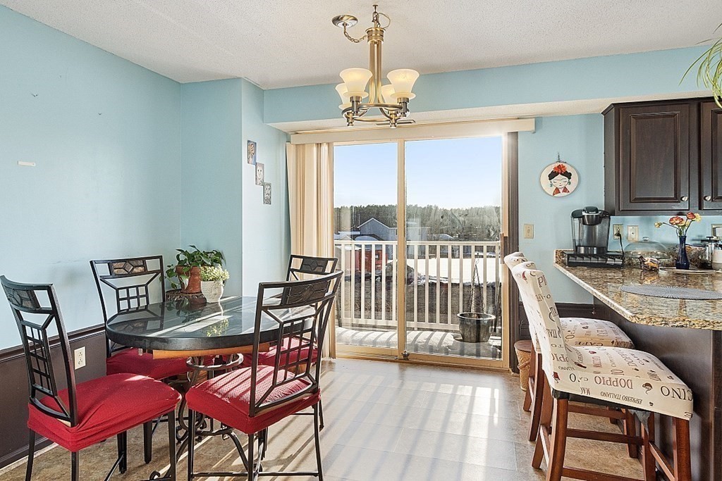 84 Century Way, Unit 84 Gardner, MA 01440 - Photo 12 of 28 a view of a dining room with furniture a chandelier and large windows