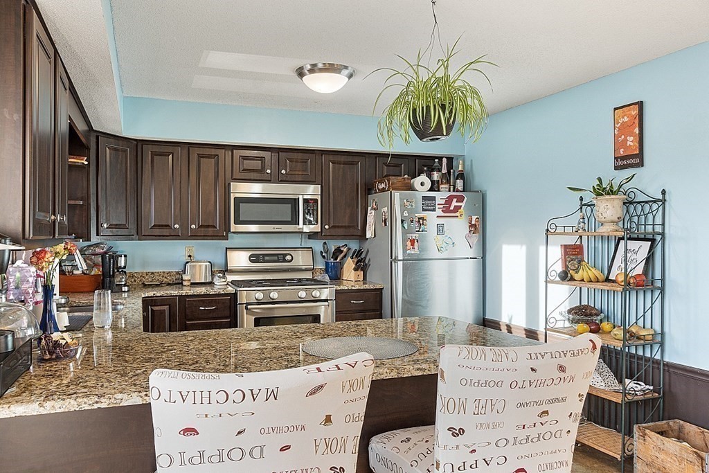 84 Century Way, Unit 84 Gardner, MA 01440 - Photo 6 of 28 a kitchen with stainless steel appliances kitchen island granite countertop a refrigerator and a stove top oven