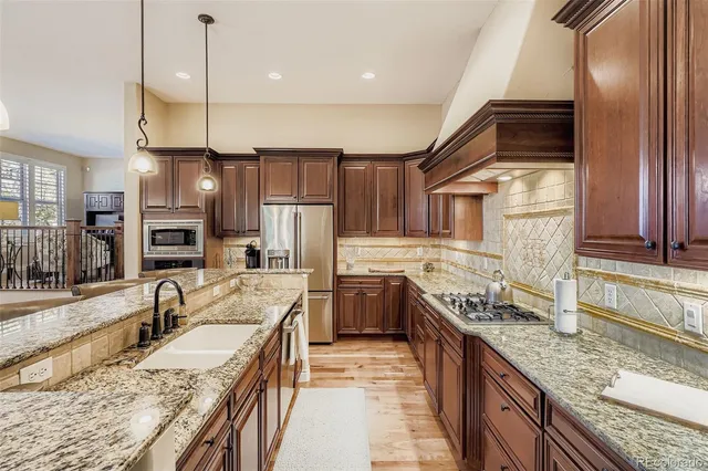 a kitchen with stainless steel appliances granite countertop a sink a stove and a refrigerator