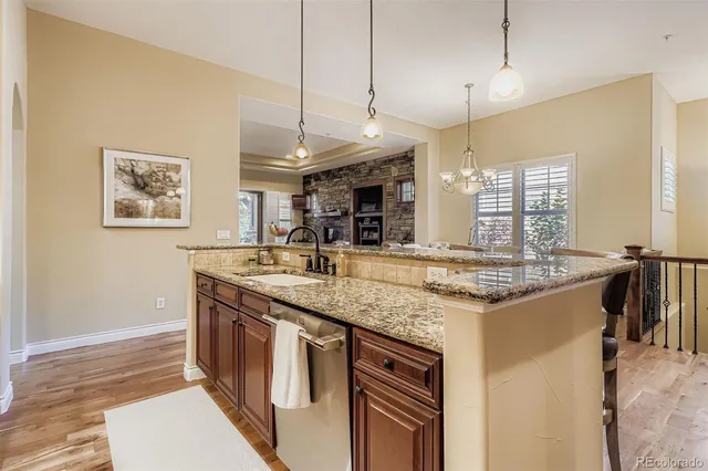 a kitchen with stainless steel appliances granite countertop a sink a stove and a wooden floor