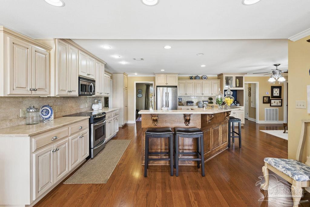 5160 Max Lane Jay, FL 32565 - Photo 3 of 54 a kitchen with stainless steel appliances kitchen island granite countertop a stove top oven a sink a refrigerator white cabinets and wooden floor
