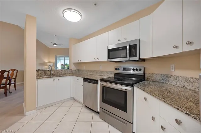 a kitchen with granite countertop white cabinets stainless steel appliances and a sink
