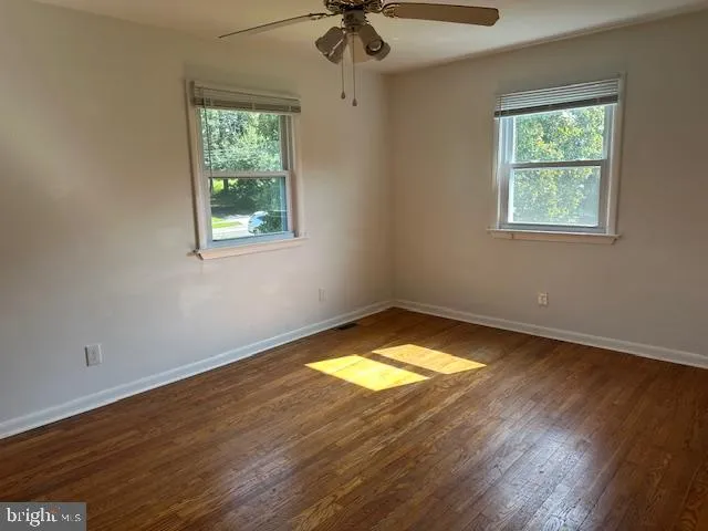 a view of empty room with wooden floor and fan