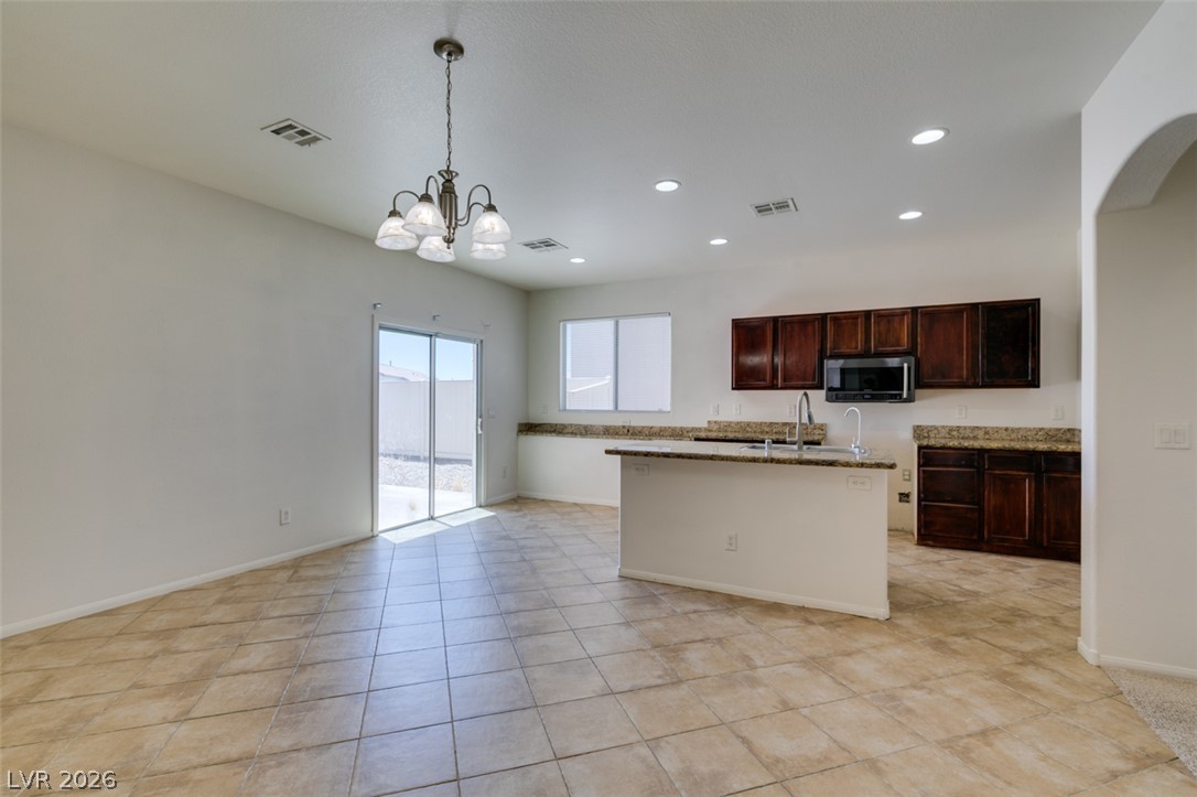 5150 Riverside Run Court North Las Vegas, NV 89081 - Photo 20 of 50 A well-lit kitchen and dining space with tile flooring, a kitchen island, and direct access to the outdoor area.