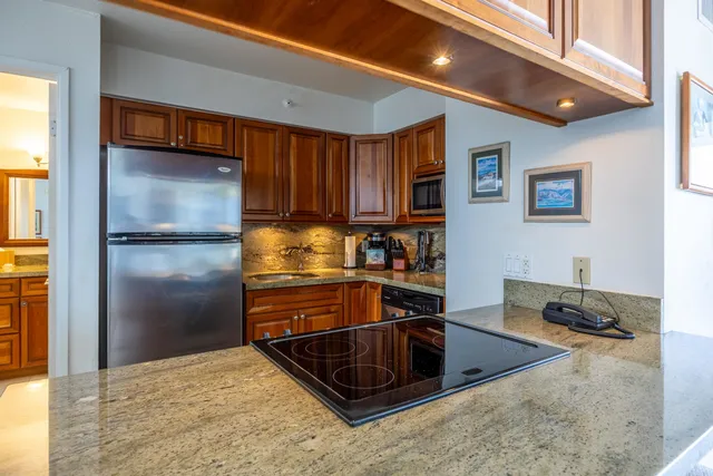 a kitchen with stainless steel appliances granite countertop a refrigerator and a stove top oven